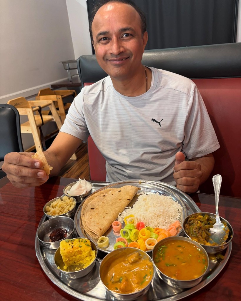 Traditional Indian thali platter with dal, curries, rice, roti, and sweet